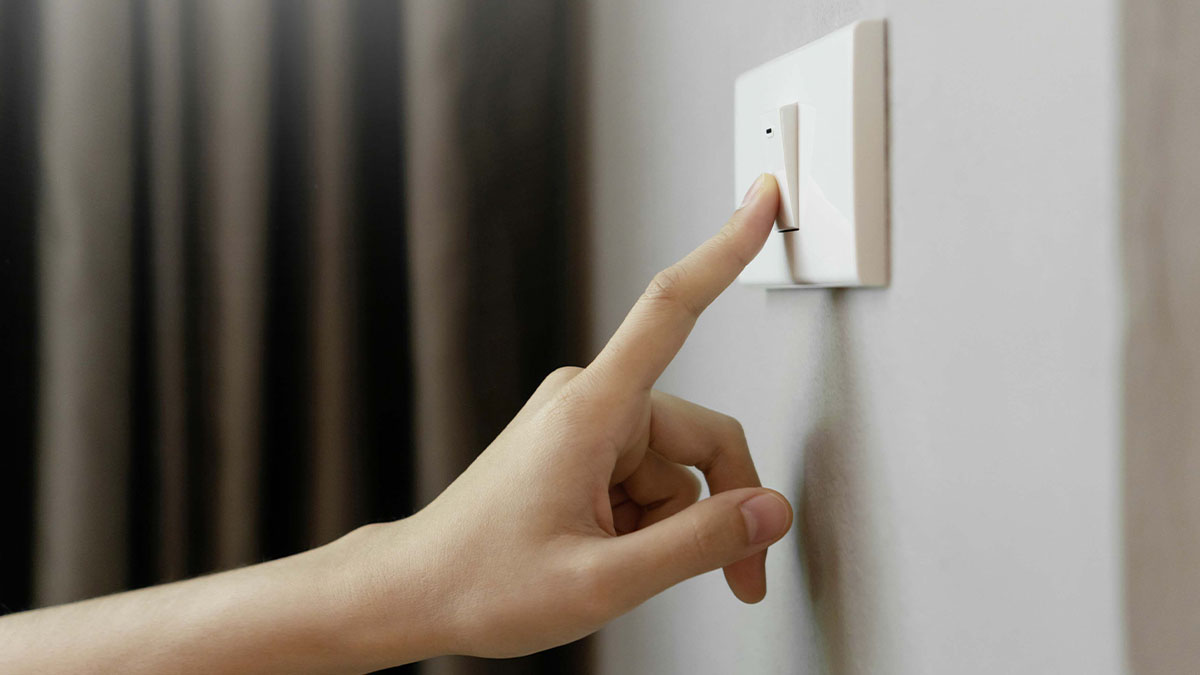 Pessoa a carregar em interruptor elétrico